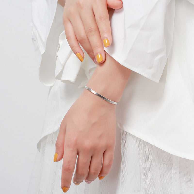 Tree of Life Studio flat snake bone silver bracelet worn on wrist with white clothing and yellow nail polish