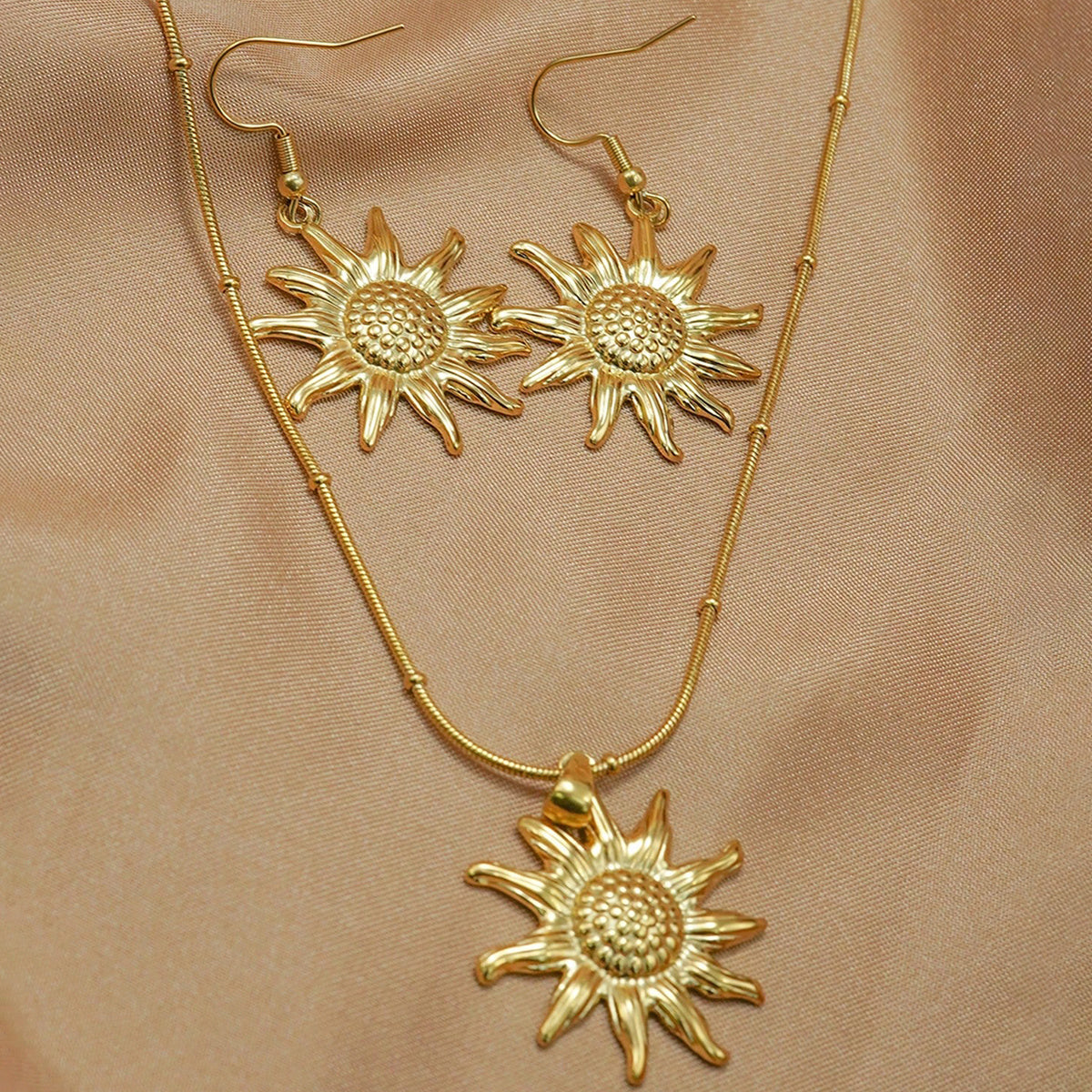 18K gold sun pendant necklace earring set hypoallergenic displayed on light brown fabric from Tree of Life Studio