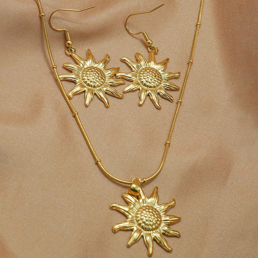 18K gold sun pendant necklace earring set hypoallergenic displayed on light brown fabric from Tree of Life Studio
