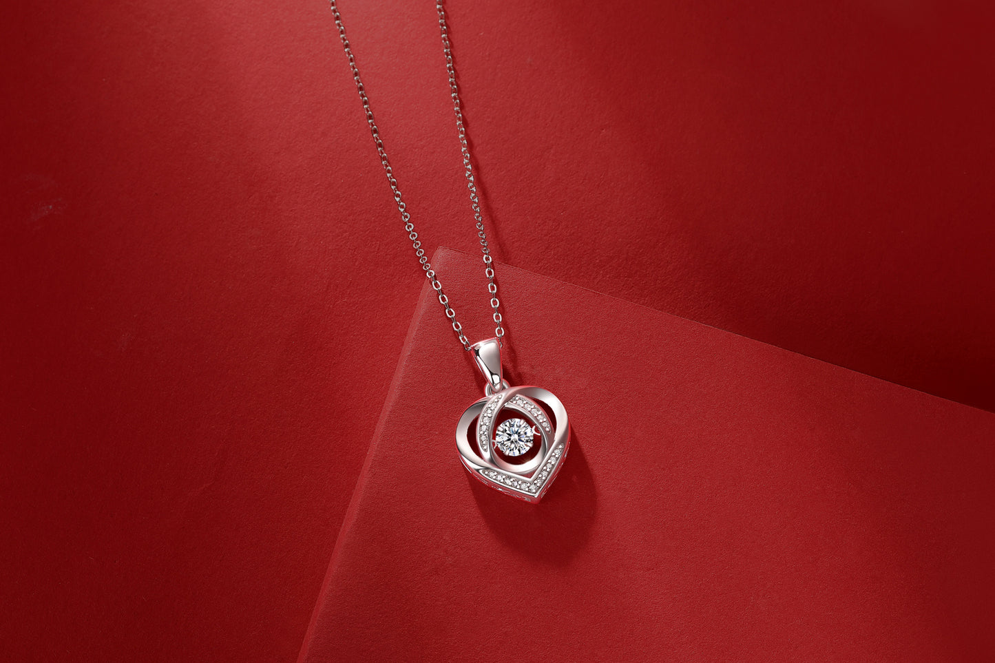 Moissanite heart necklace for women with silver chain and sparkling center stone on red background