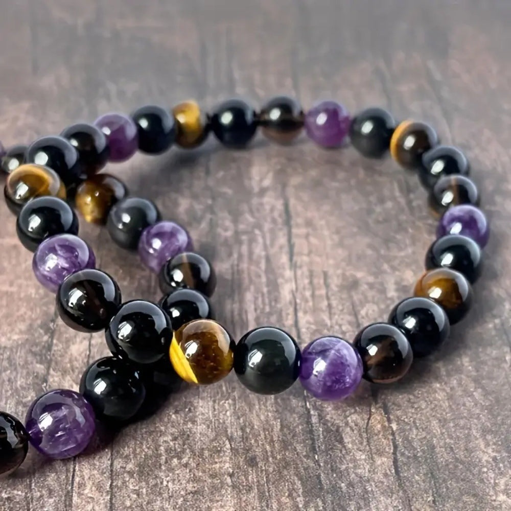 Tree of Life Studio spiritual protection gemstone bracelet with amethyst, tiger eye, and black beads on wooden surface