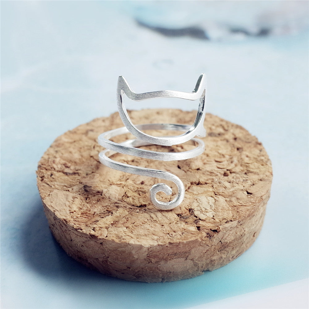 Sterling silver cat ring from Tree of Life Studio with minimalist open design on cork background