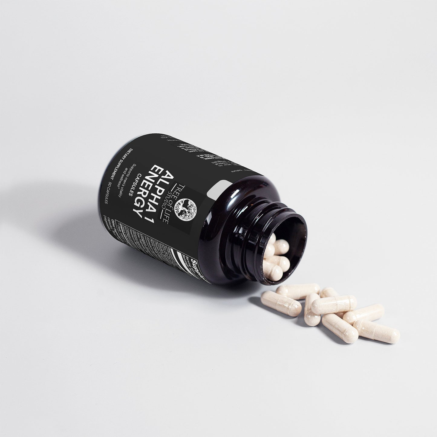 Tree of Life Studio Alpha 1 Energy supplement bottle with white capsules spilling out on white background