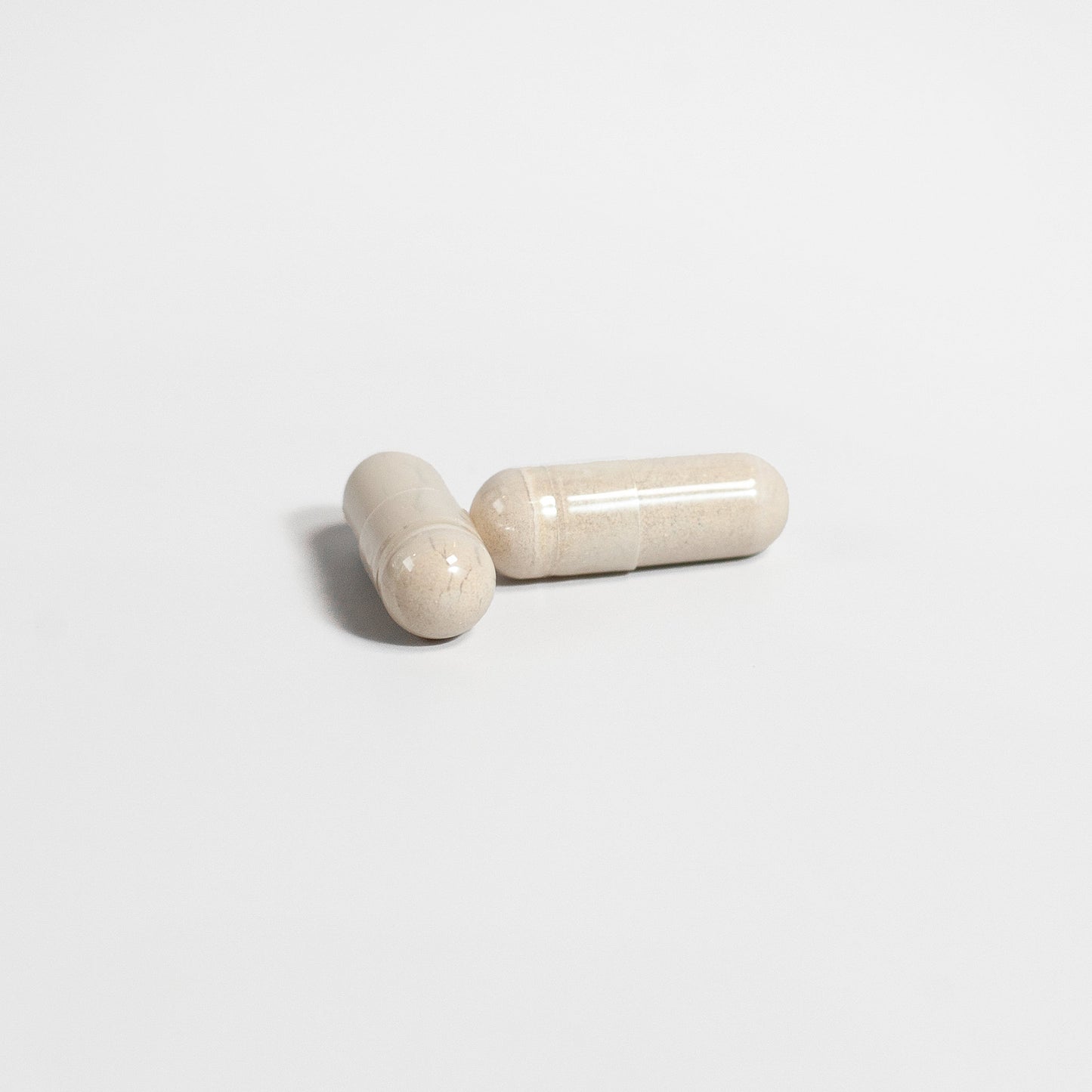 Two beige capsules of Tree of Life Studio Alpha 1 Energy supplement on a white background