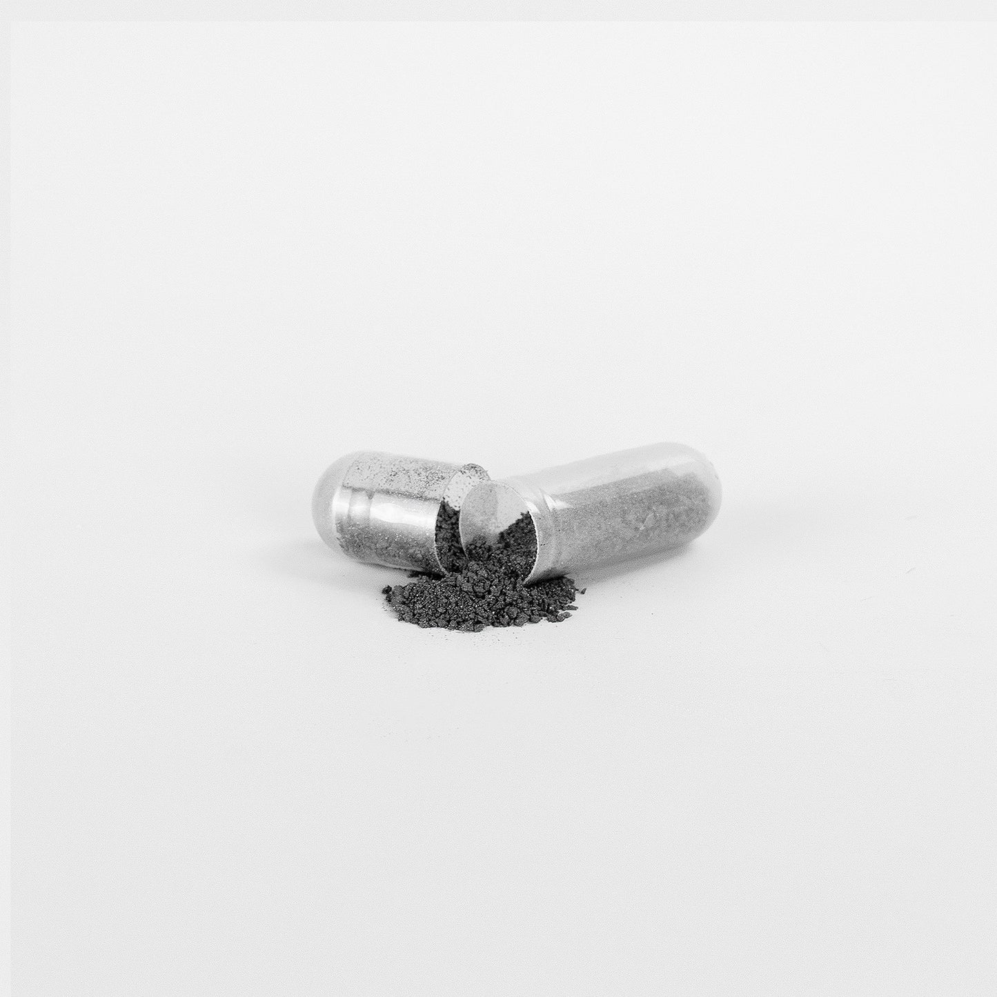Natural gut wellness supplement capsule with black powder spilled out on white background