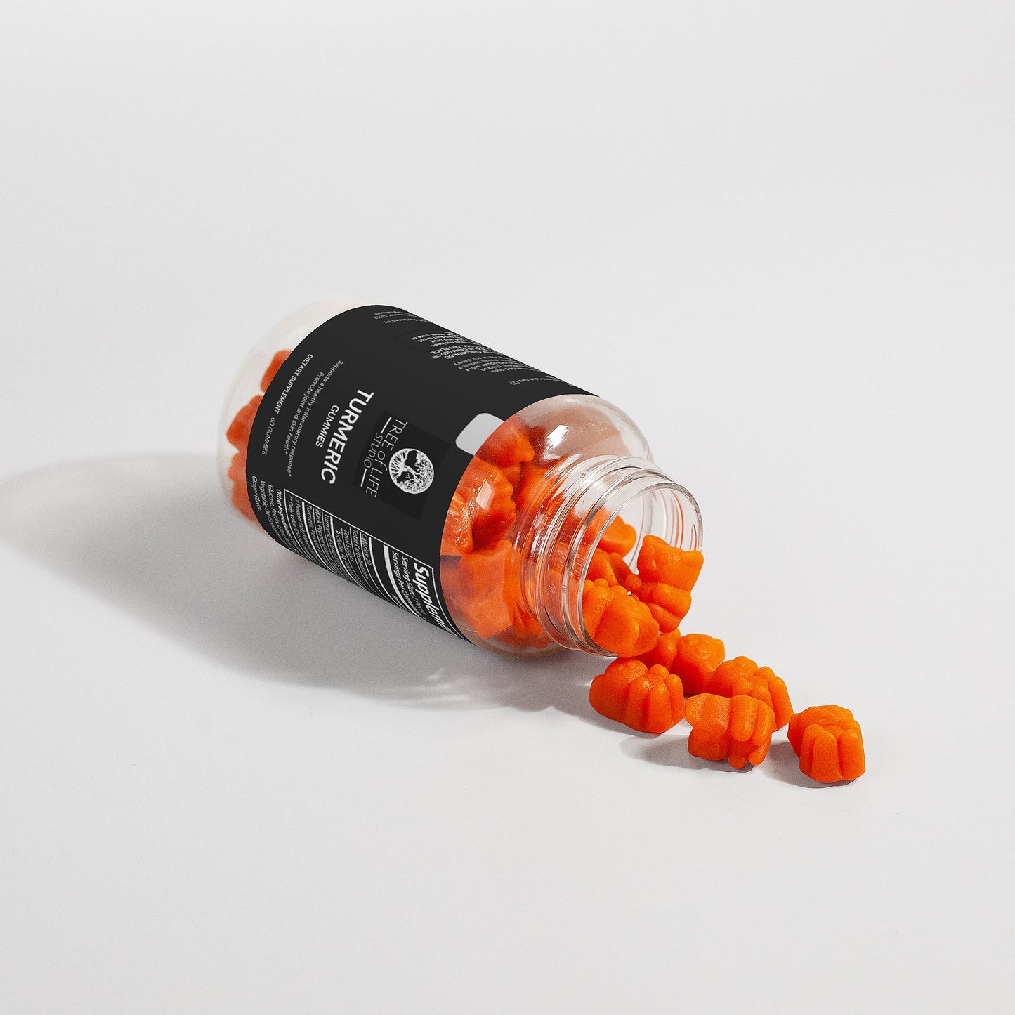 Tree of Life Studio premium turmeric gummies USA spilling from a clear bottle on white background