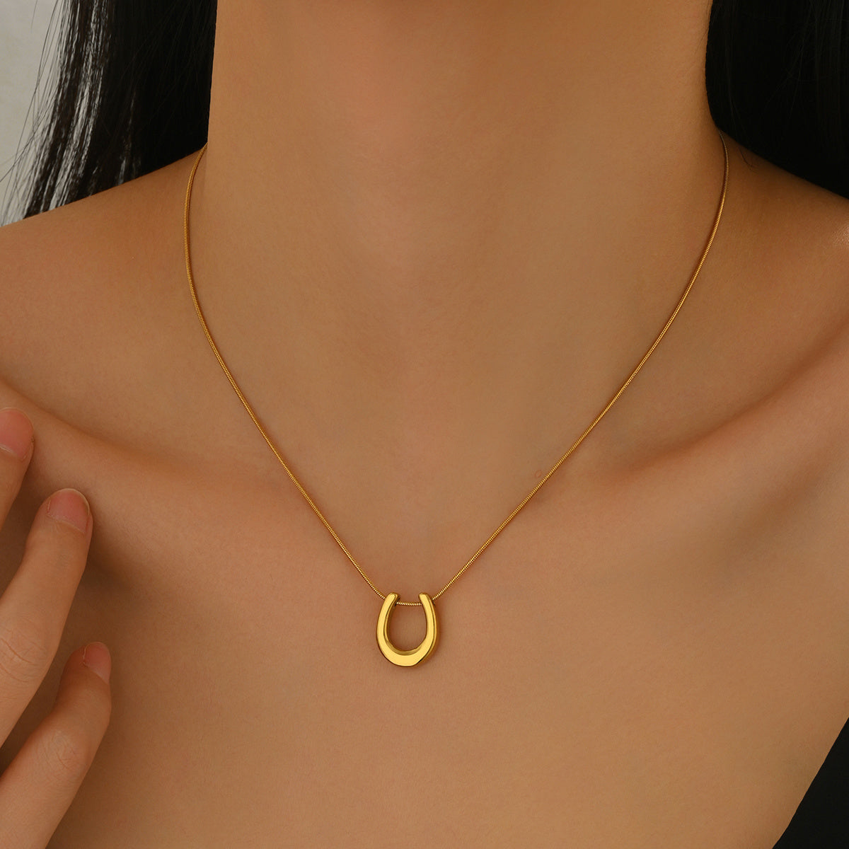 18K gold horseshoe necklace from Tree of Life Studio worn on model’s neck with delicate chain