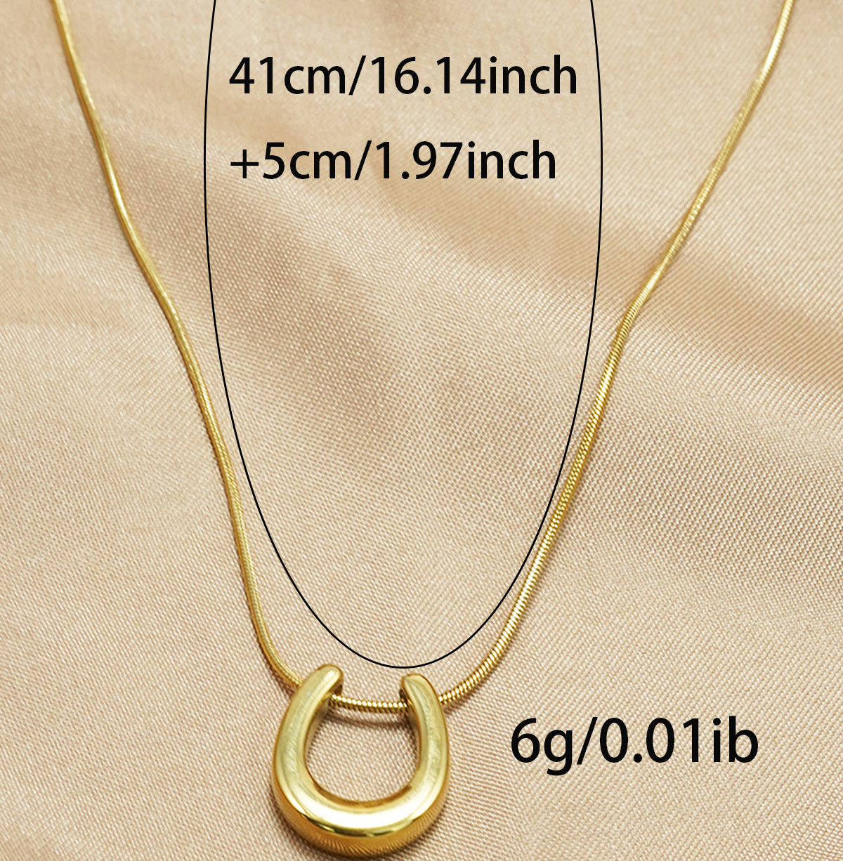 18K gold horseshoe necklace by Tree of Life Studio with adjustable chain on beige fabric background