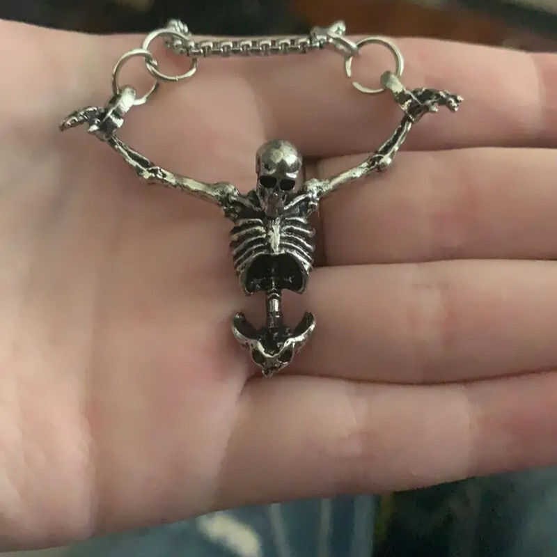 Tree of Life Studio spiritual skeleton necklace held in hand with detailed silver skeleton design