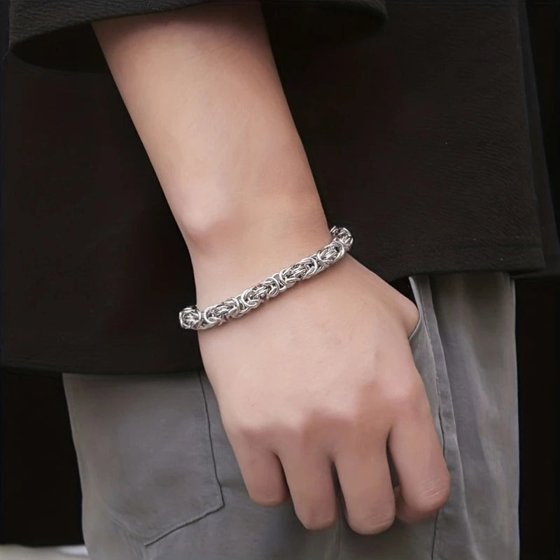 Braided stainless steel link bracelet worn on wrist by person in casual outfit