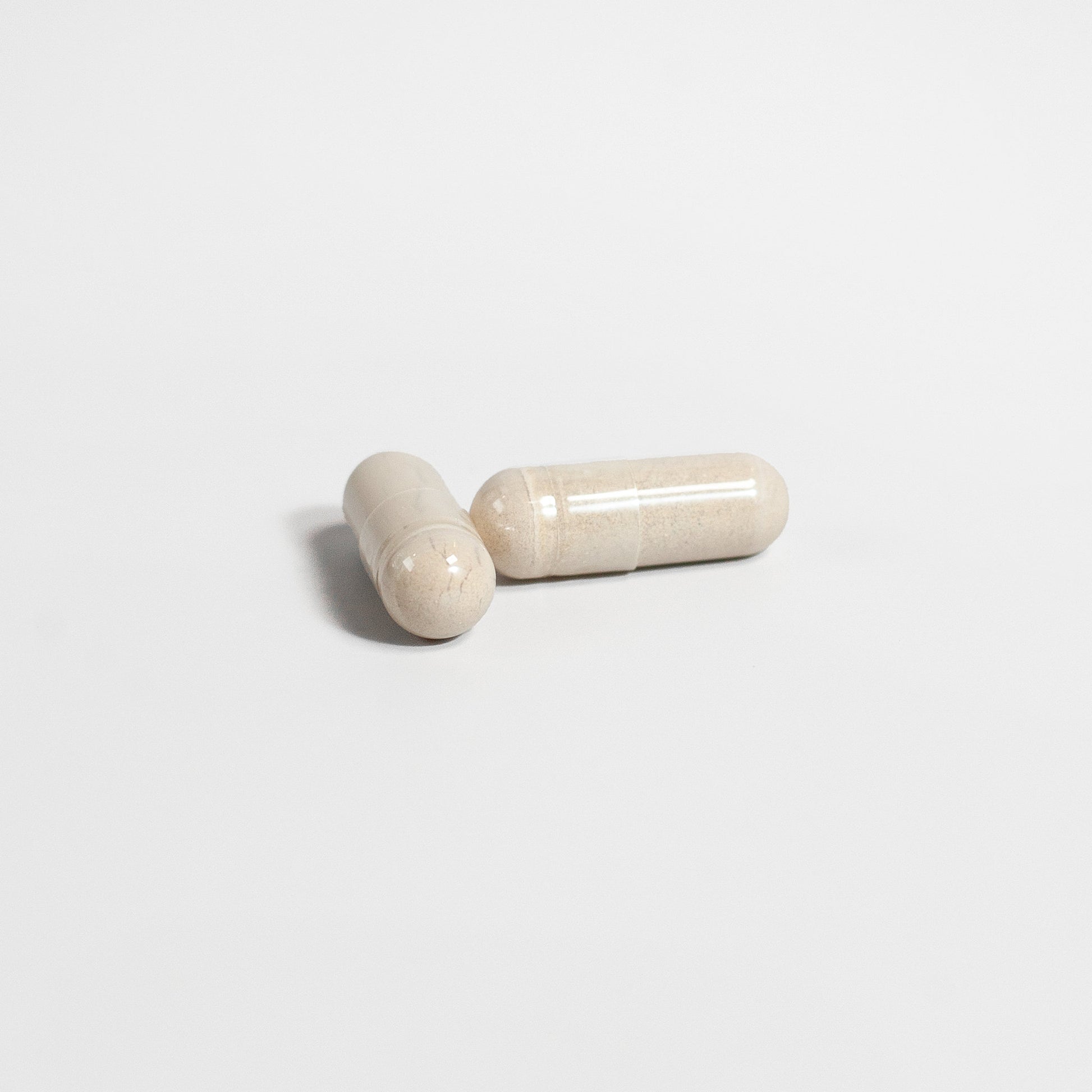 Two beige capsules of Tree of Life Studio Alpha 1 Energy supplement on a white background
